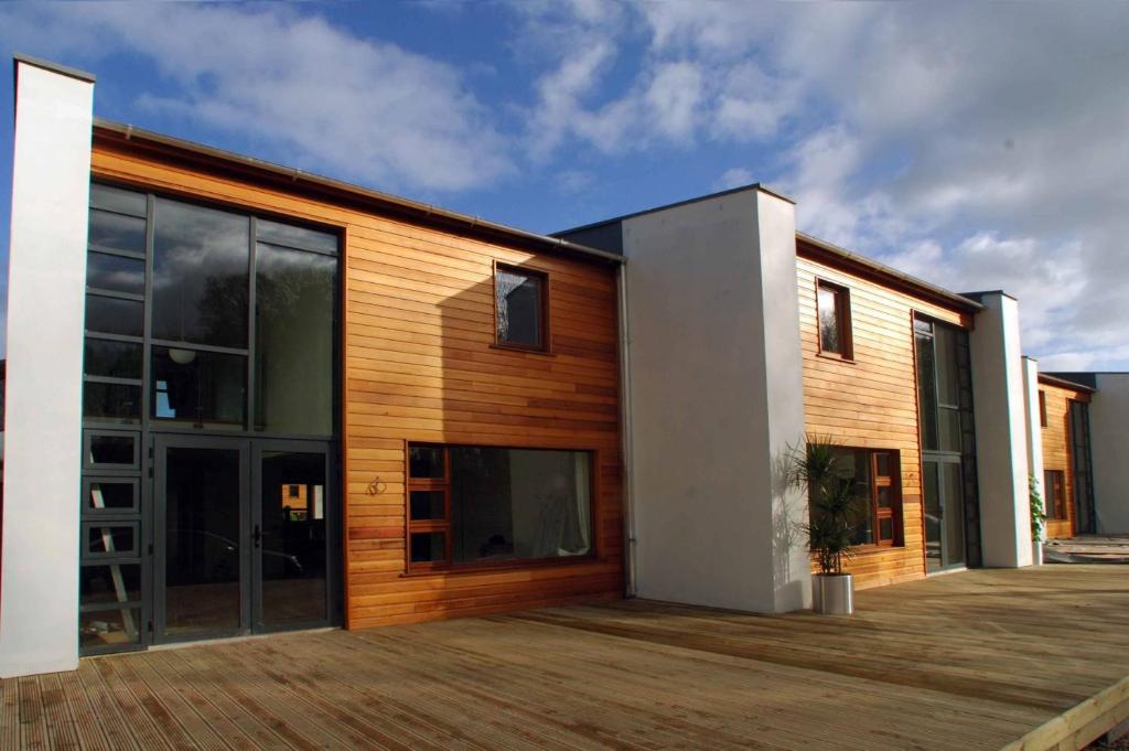 une maison avec une façade en bois et une terrasse dans l'établissement Castlemartyr Holiday Lodges 2 Bed, à Castlemartyr