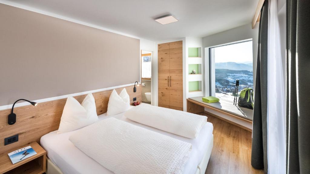 a bedroom with a white bed and a large window at Putzerhof in Siusi