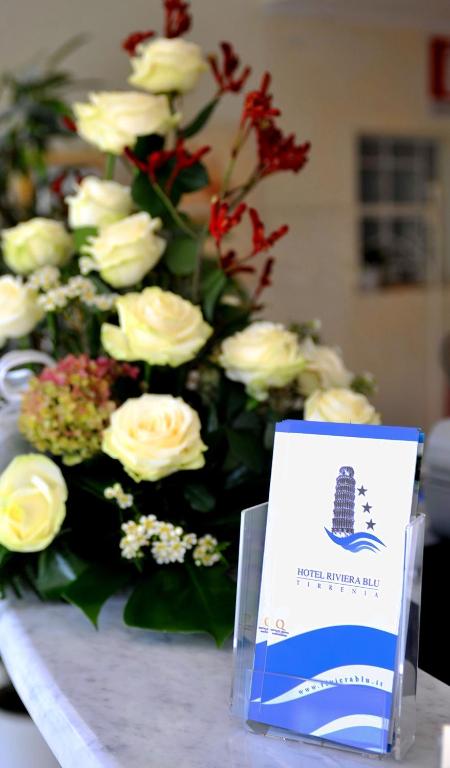 a table with a bouquet of white roses and a sign at Hotel Riviera Blu in Tirrenia