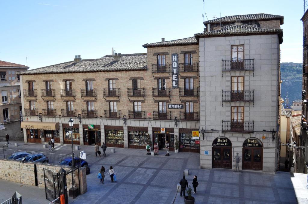 a large building with people walking in front of it at Hotel Sercotel Alfonso VI in Toledo