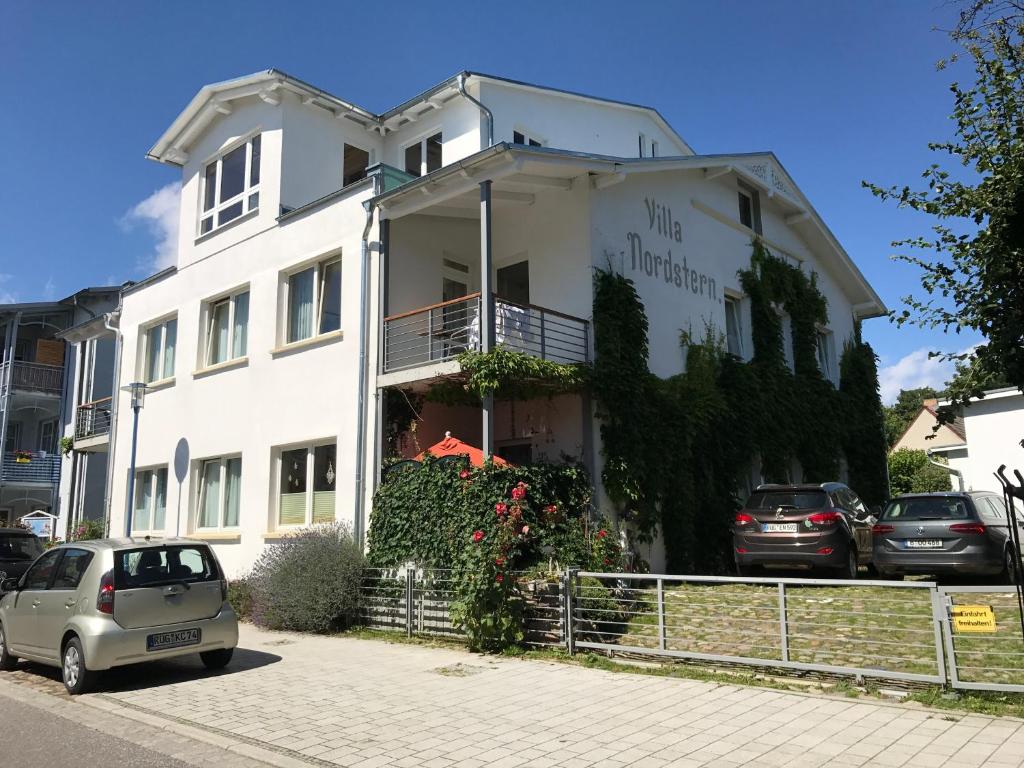 a white building with a small car parked in front at Villa Nordstern in Göhren