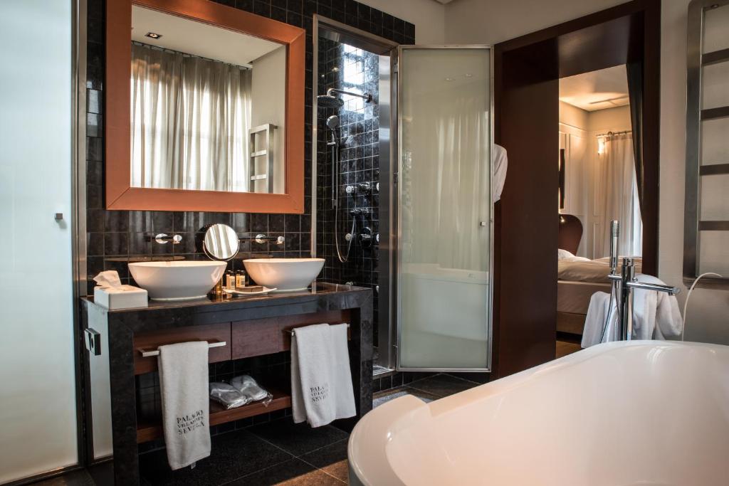 a bathroom with a tub, sink and mirror at CoolRooms Palacio Villapanés in Seville