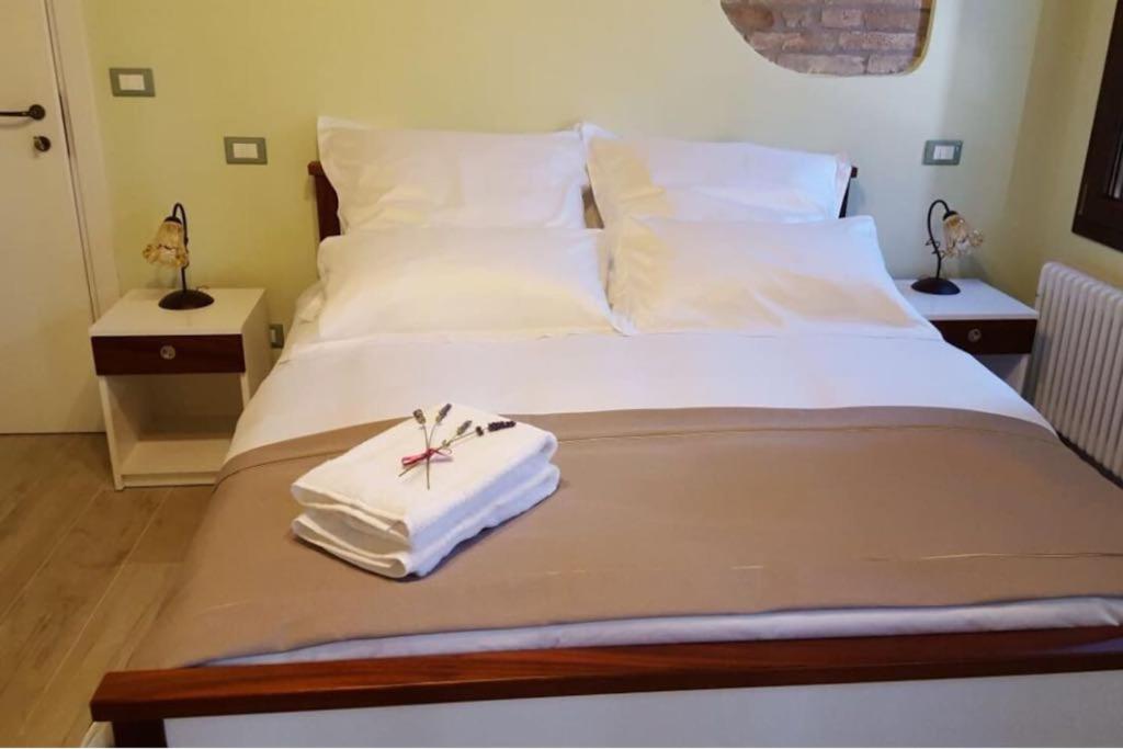 ein Bett mit weißer Bettwäsche und einem Handtuch darauf in der Unterkunft Dal Marinaio in Comacchio