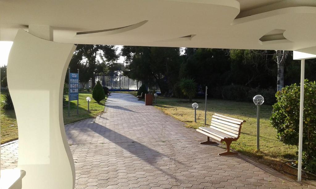 a park bench sitting on a brick walk way at Parthenis Riviera Hotel in Athens