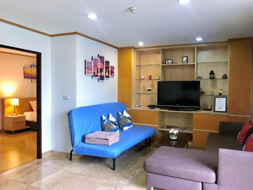 a living room with a blue chair and a tv at Twin Peaks Sukhumvit Suites in Bangkok