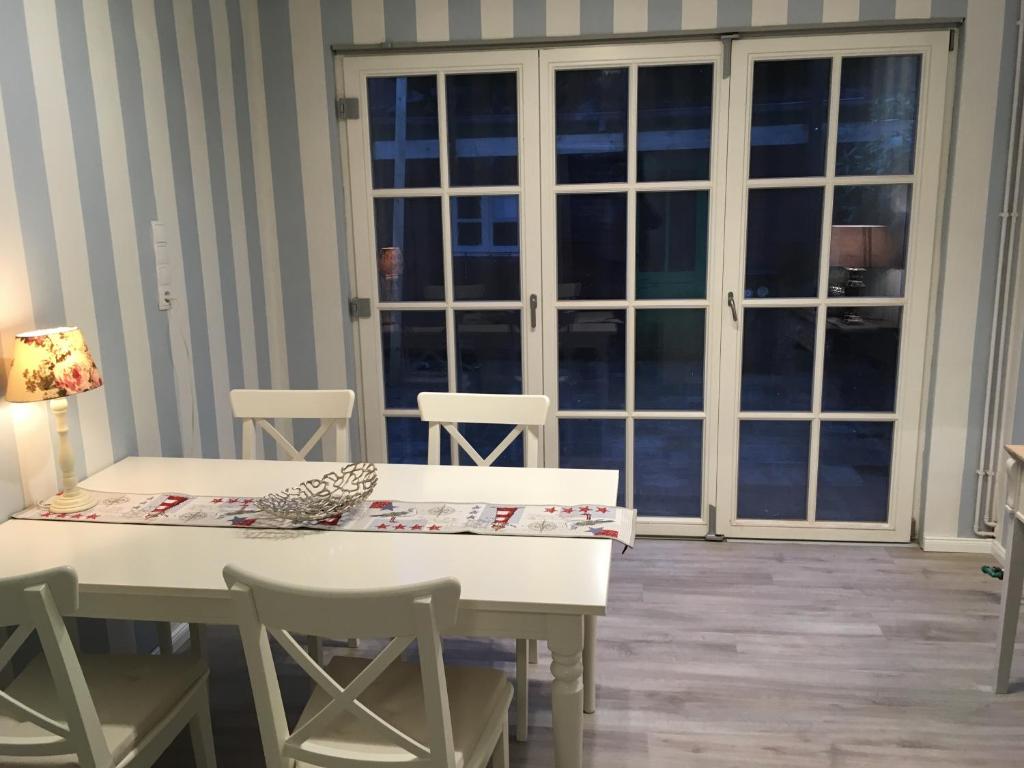 una mesa y sillas blancas en una habitación con ventana en Ferienhaus Witte Huuske, en Emden