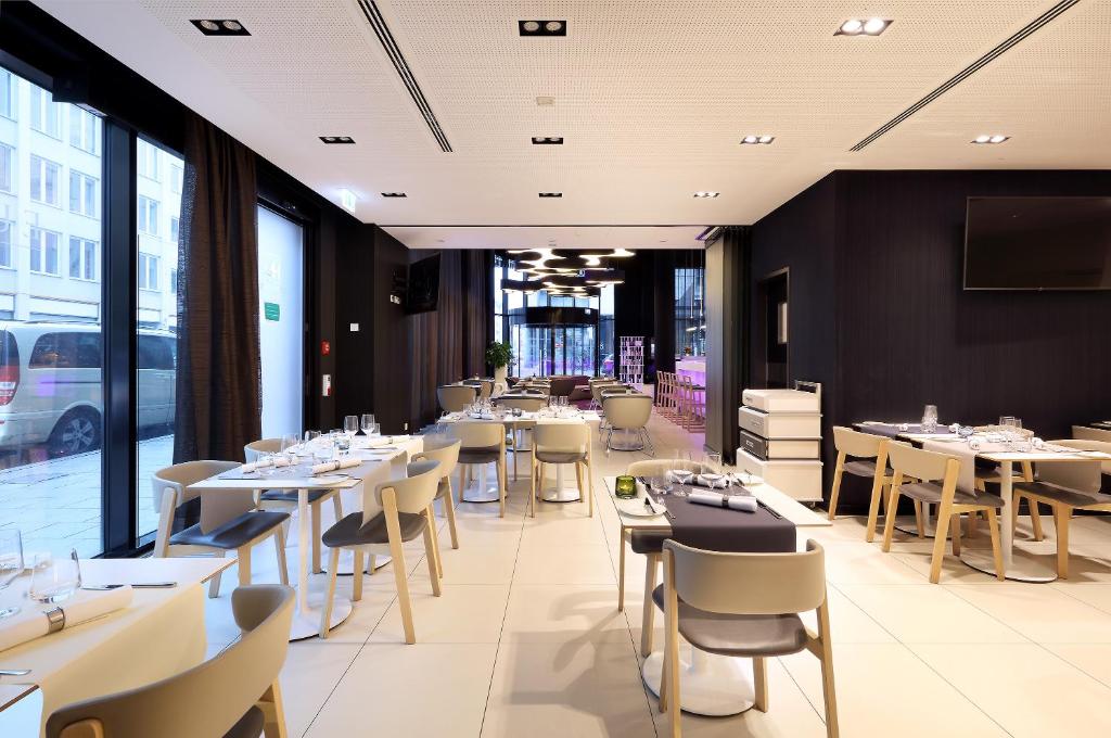 a restaurant with white tables and chairs and windows at Eurostars Book Hotel in Munich