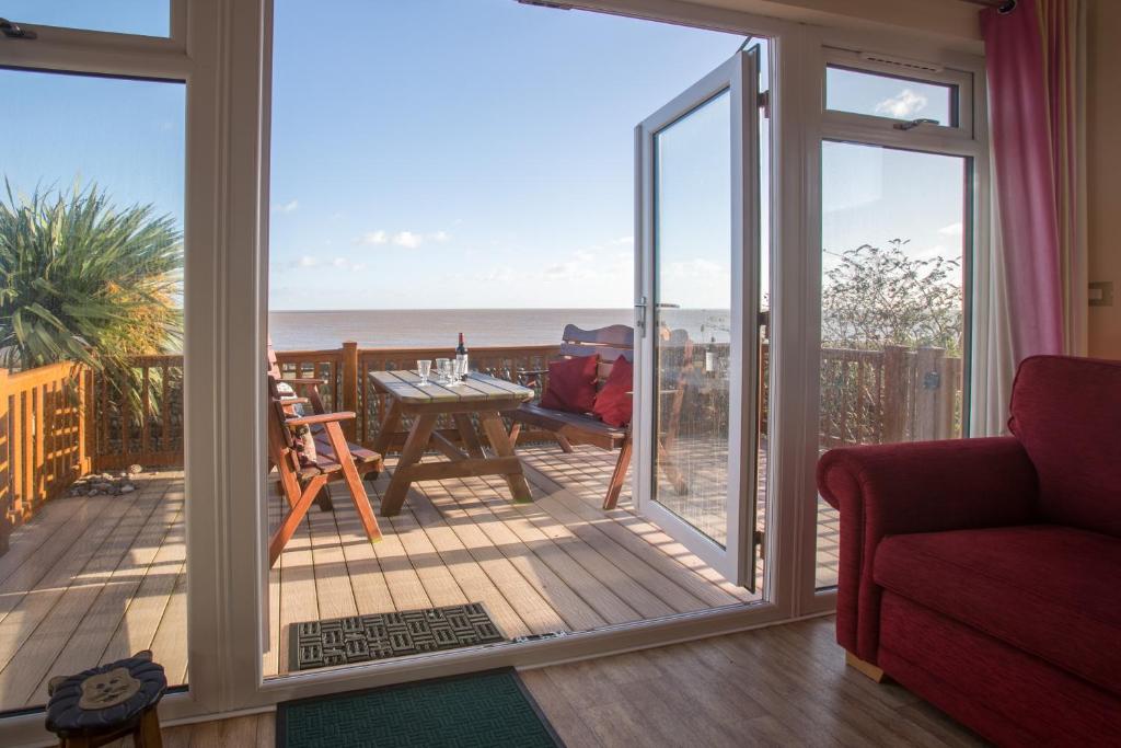 a living room with a sliding glass door with a view of the ocean at Sole Bay View in Sizewell