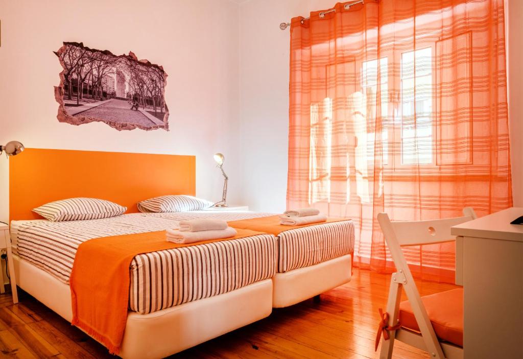 um quarto com uma cama com uma cabeceira laranja e uma janela em Loulé Coreto Hostel em Loulé