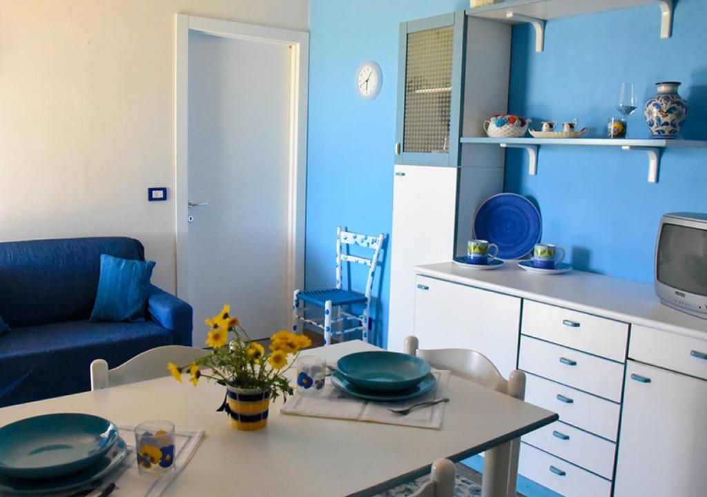 ポルトパーロにあるCasa Vacanze Portopalo di Capopasseroの青い壁のキッチン(テーブル、皿付)