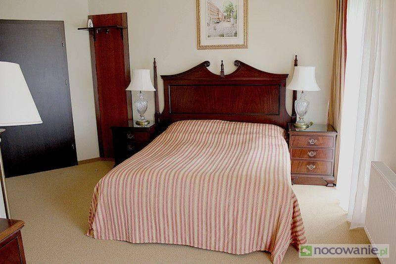オポーレにあるArkadia Gościniecのベッドルーム1室(ストライプ毛布とランプ2つ付)