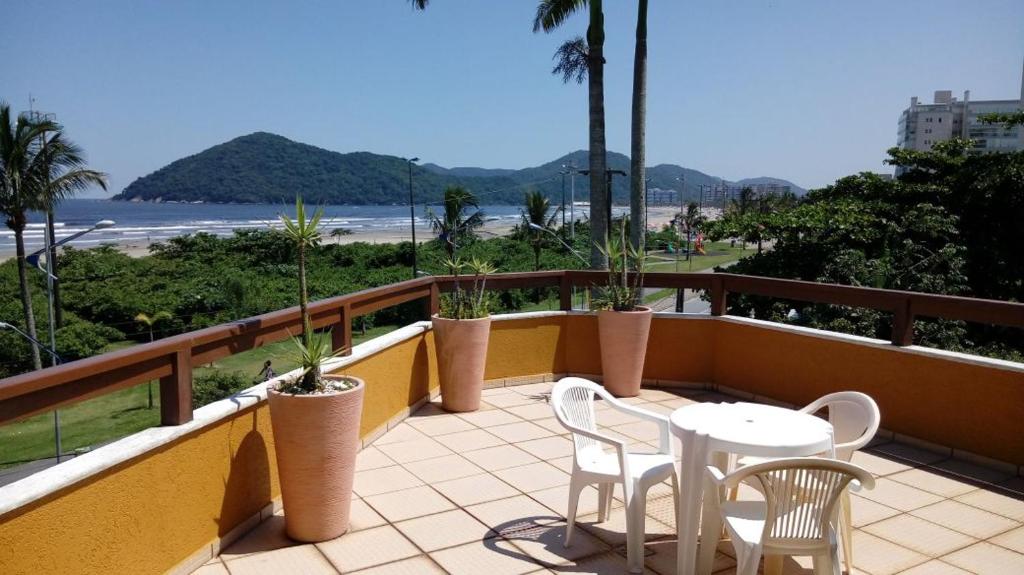 a balcony with tables and chairs and a view of the beach at Pousada Mirante da Enseada in Bertioga
