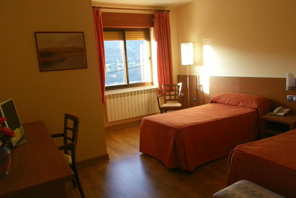 a hotel room with two beds and a window at Hotel Don Pepe Lago de Sanabria in Ribadelago