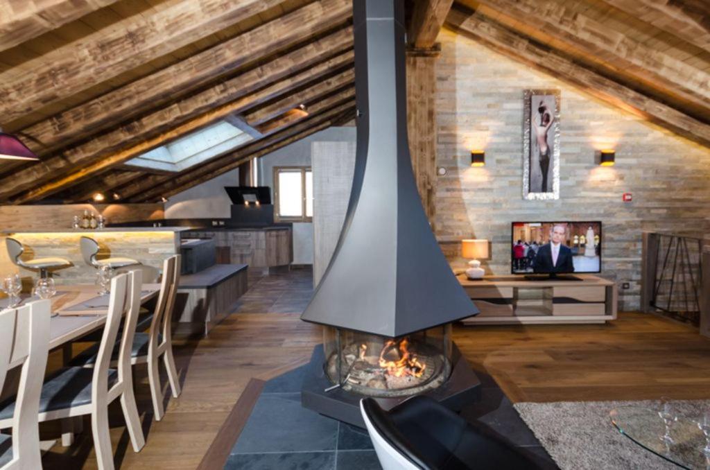a fireplace in the middle of a living room with a table at Chalet Emilie in Courchevel