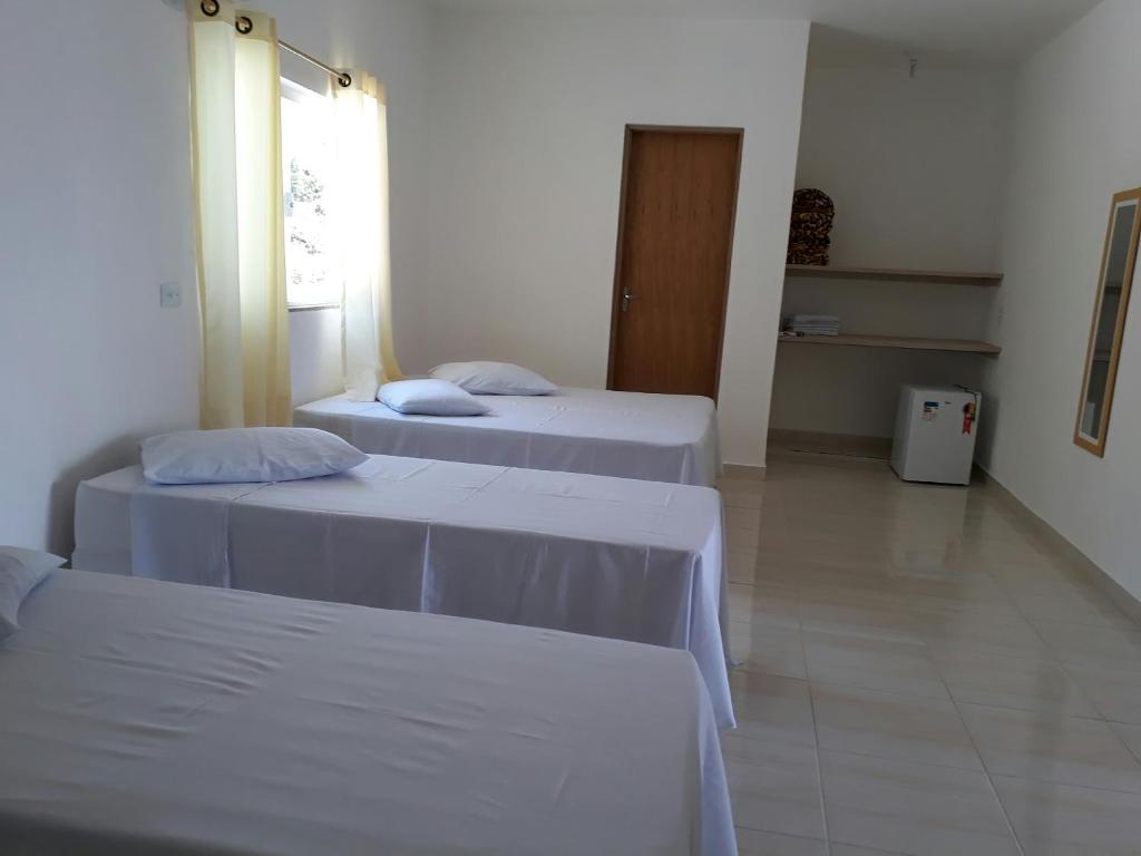 Habitación con 2 camas con sábanas blancas y ventana en Pousada GEF Aparecida, en Aparecida