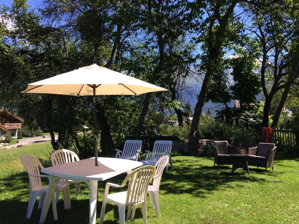 a table and chairs with an umbrella in the grass at Chalet Emilie in Courchevel