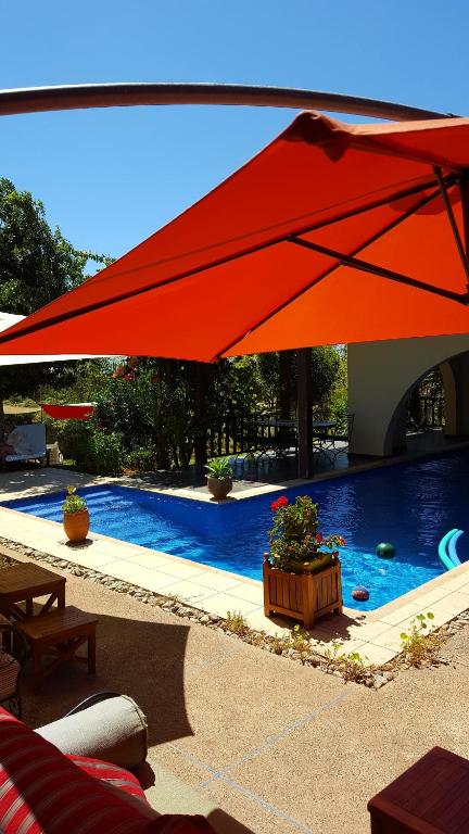 a large red umbrella over a swimming pool at L'échappée belle Benslimane in O Ben Slimane