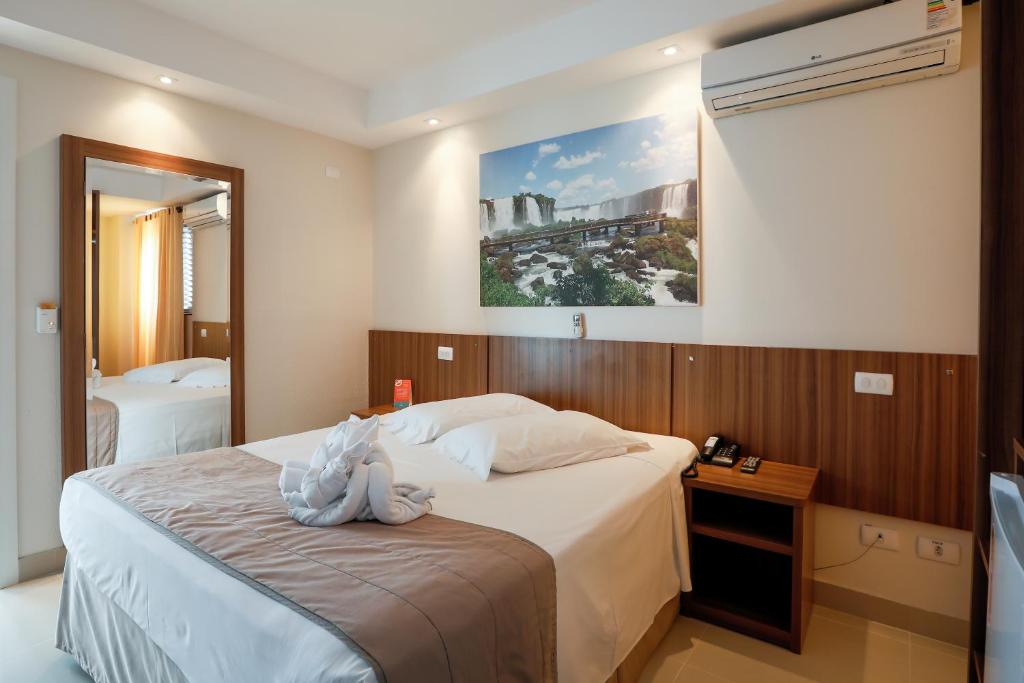 ein Hotelzimmer mit einem Bett und einem Spiegel in der Unterkunft Del Rey Quality Hotel in Foz do Iguaçu