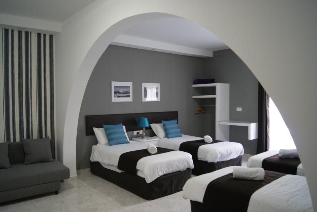 Habitación de hotel con 2 camas y sofá en Buccaneers Boutique Guest House en St. Paul's Bay