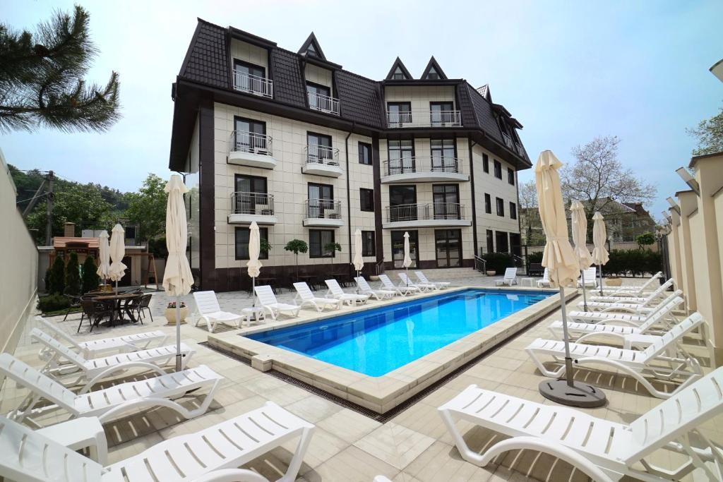 ein Hotel mit einem Pool und Stühlen sowie einem Gebäude in der Unterkunft Hotel Admiral in Olginka