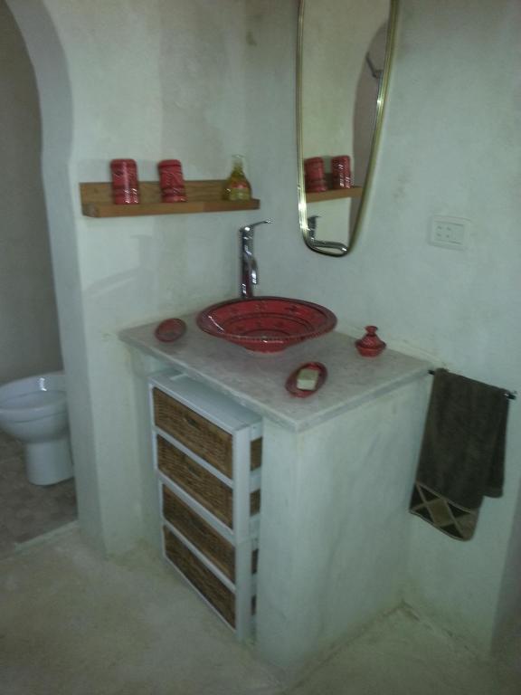 a bathroom with a red sink and a mirror at Menzel Churasco Djerba in Aghīr