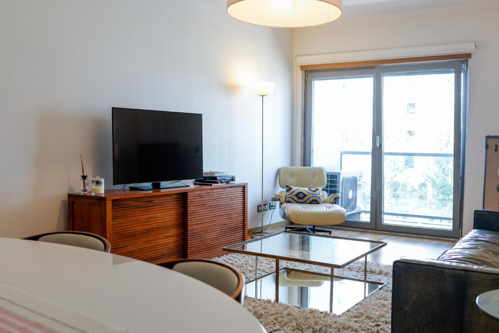 uma sala de estar com uma televisão de ecrã plano e um sofá em Lisbon White Cozy Apartment em Lisboa
