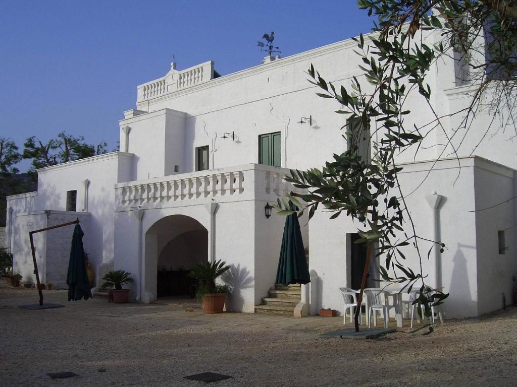 a white building with an archway and a building with umbrellas at Masseria Trotta B&B in Fasano