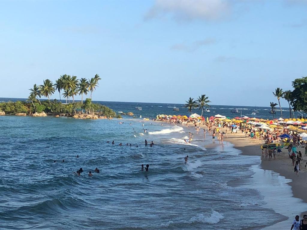 a group of people on a beach with umbrellas at Pousada e Camping América in Morro de São Paulo