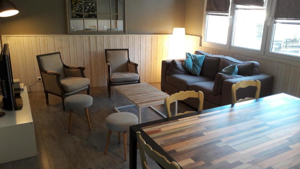 a living room with a couch and chairs and a table at la maison du postier in Port-en-Bessin-Huppain