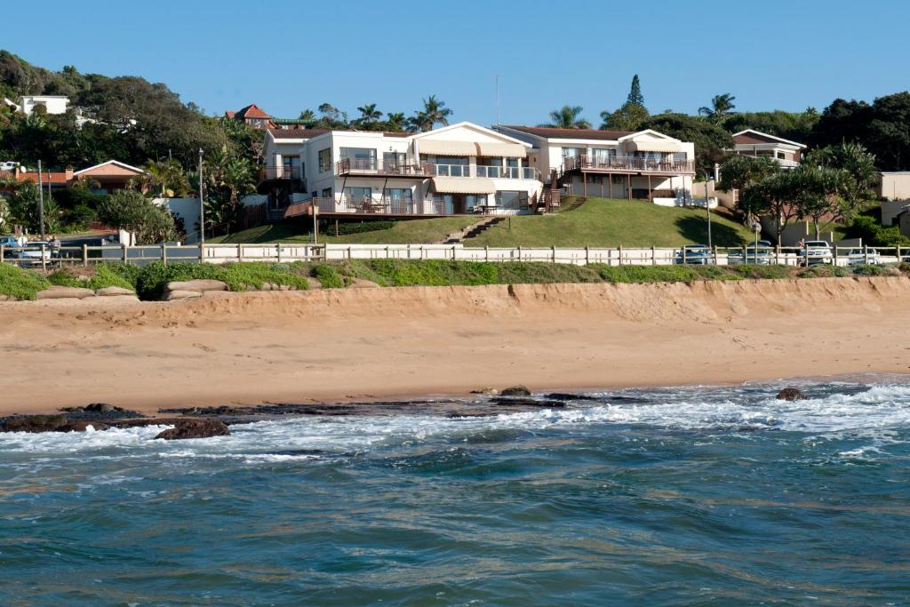 a house on the beach next to the ocean at Fairlight Beach House in Umdloti