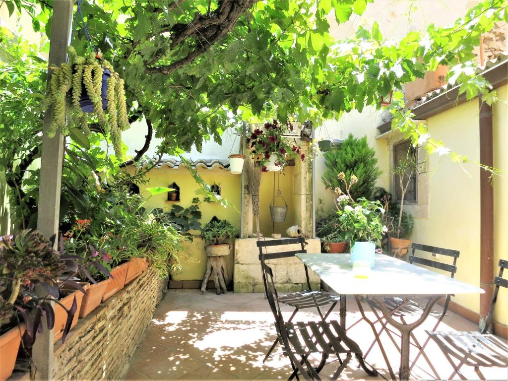 シラクーサにあるLa Casa Delle Fateの植物のある中庭にテーブルと椅子