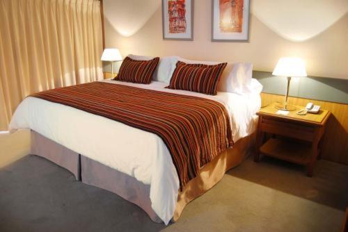 uma cama grande num quarto de hotel com duas lâmpadas em Hotel Conte em Buenos Aires