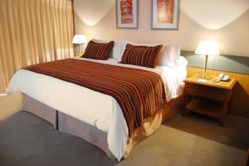 a large bed in a hotel room with two lamps at Hotel Conte in Buenos Aires