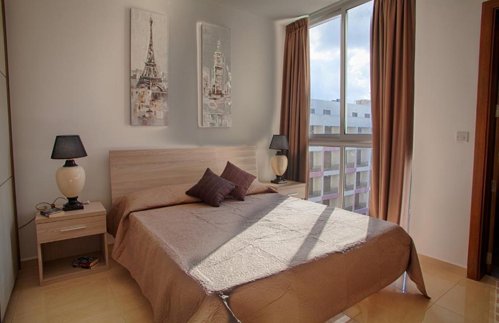 ein Schlafzimmer mit einem Bett und einem großen Fenster in der Unterkunft The Edge Apartments in St Paul's Bay