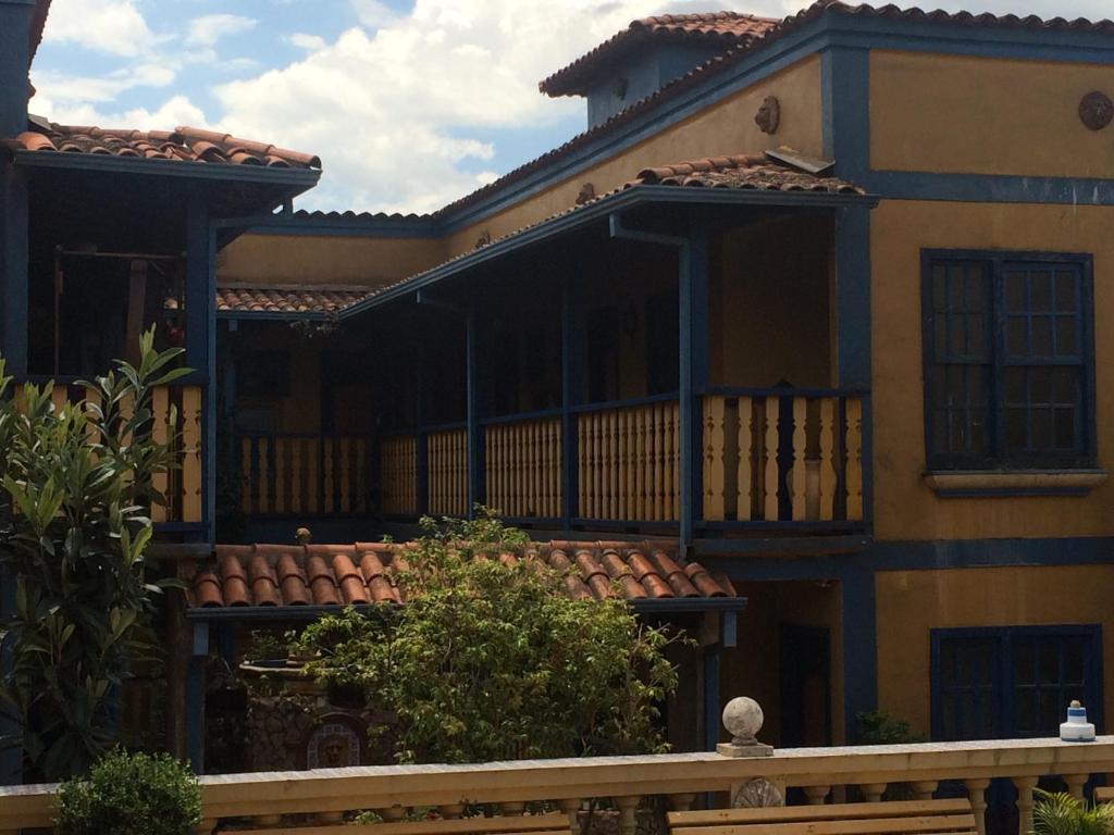Pousada Casarão da Pedra في كونجونهاس: منزل أصفر كبير مع شرفة كبيرة