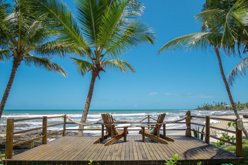 two chairs sitting on a boardwalk next to the beach at Back Door Village in Olivença