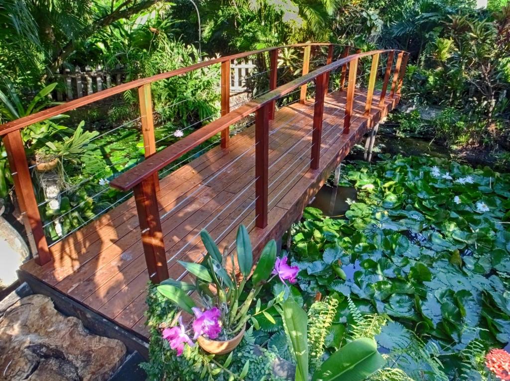 a wooden bridge over a pond with flowers and plants at Le Parc aux Orchidées in Pointe-Noire