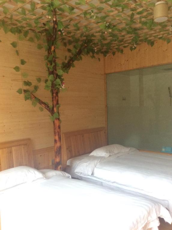 a bedroom with two beds and a tree on the wall at Yangjiajie Inn in Zhangjiajie