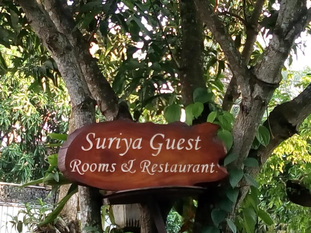 a sign for a guest rooms and restaurant next to a tree at Suriya Homestay Mirissa in Mirissa