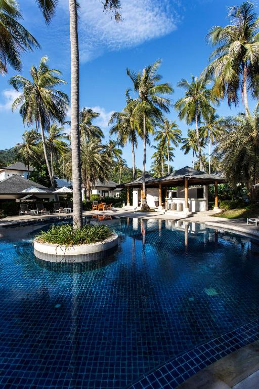 a swimming pool at a resort with palm trees at The Racha in Ko Racha Yai 
