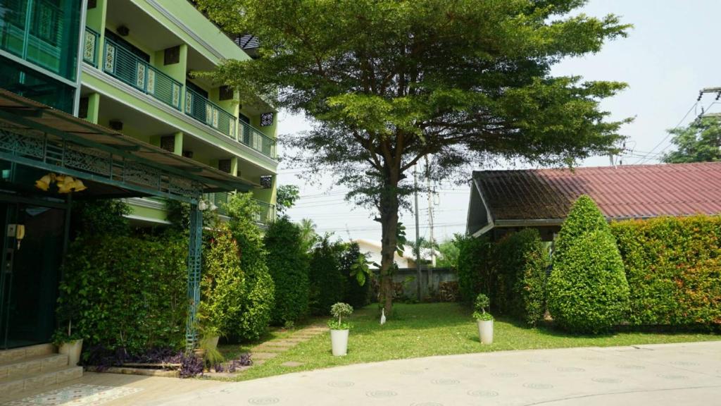 a yard of a building with a tree and bushes at Garden Corner Resort & Hotel in Phitsanulok