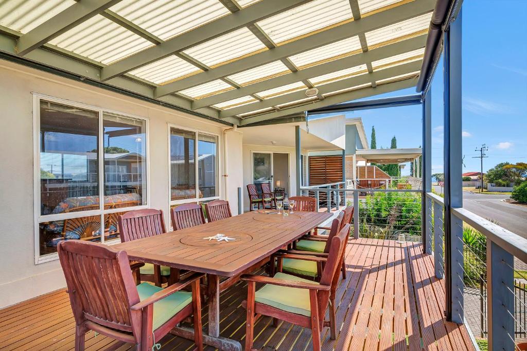 a patio with a wooden table and chairs on a deck at Green Reef Beach House in Aldinga Beach