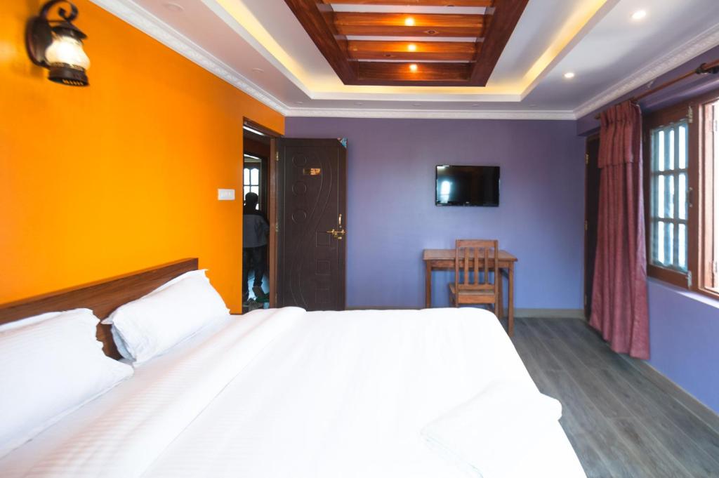- une chambre avec un lit blanc et un mur orange dans l'établissement Be Here Now, à Katmandou