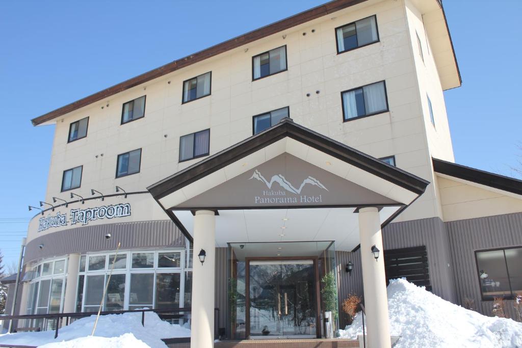 a hotel with snow in front of a building at Hakuba Panorama Hotel in Hakuba