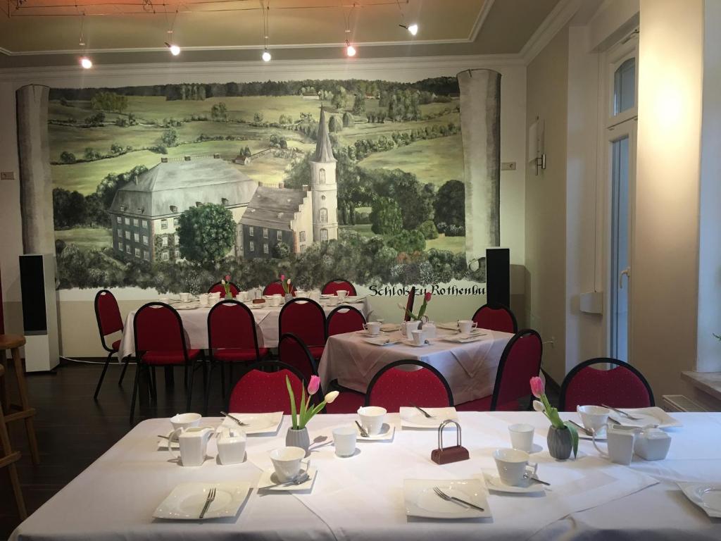 a room with tables and red chairs and a painting at Zum Postamt in Rothenburg