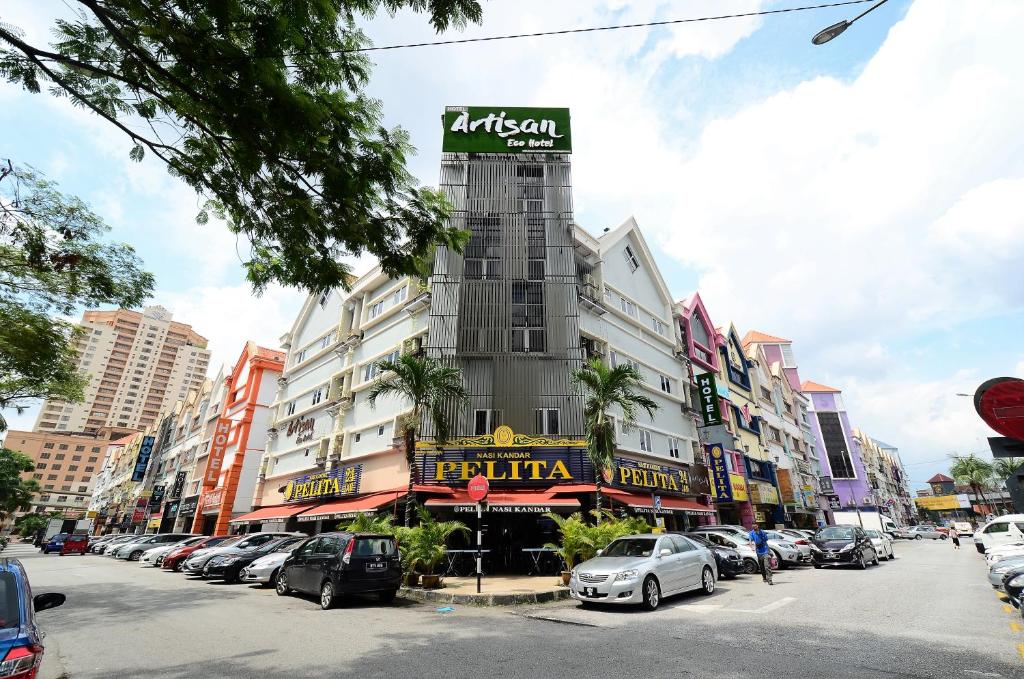 ein Gebäude auf einer Straße mit Autos auf einem Parkplatz in der Unterkunft Artisan Eco Hotel in Petaling Jaya