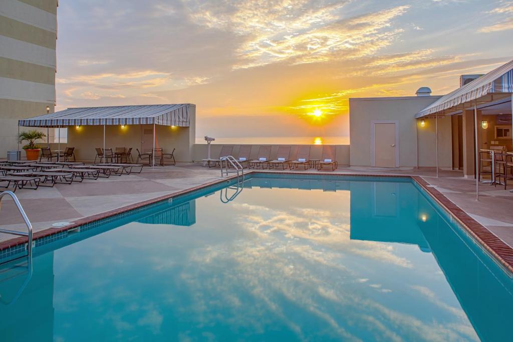 a pool with tables and chairs and a building at Beach Quarters Resort in Virginia Beach