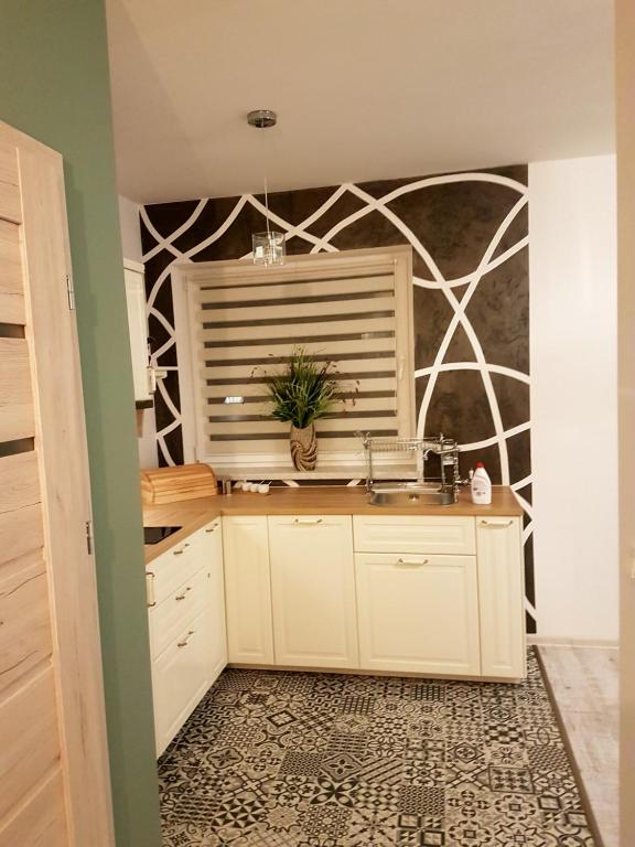 una cocina con fregadero y una pared de mosaico en Apartament Nowe Maniowy, en Maniowy