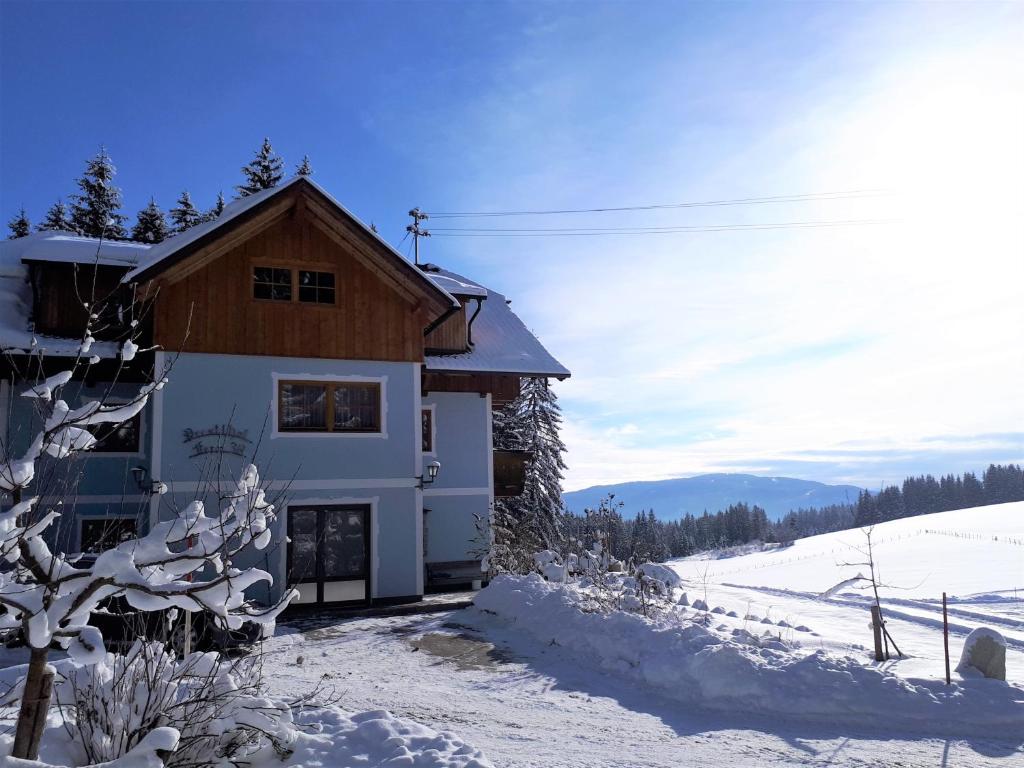 una casa con nieve en el suelo junto a un edificio en Prestlhof, en Mariapfarr