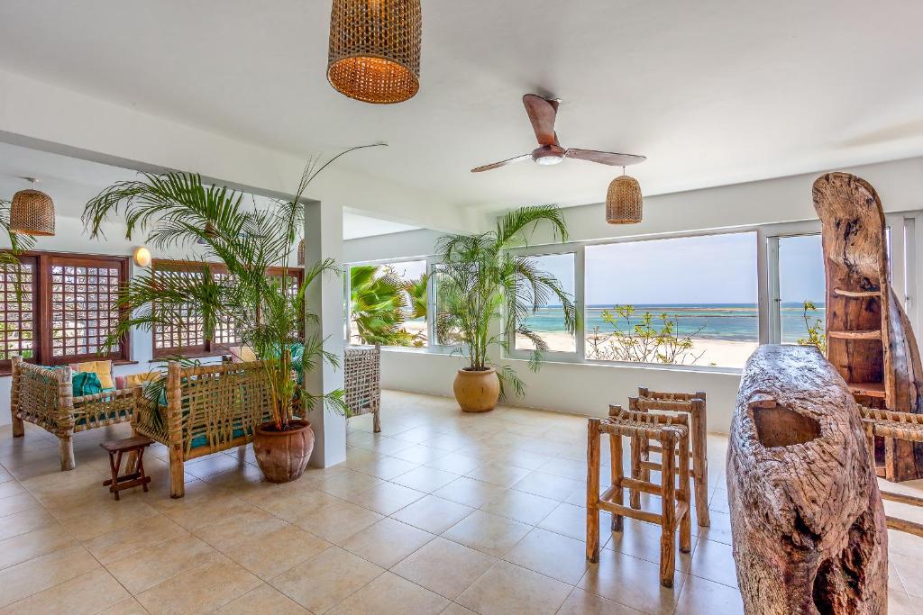 Tequila Sunrise Beach Cabana - Diani Beach في شاطئ دياني: غرفة معيشة مع طاولة وكراسي ونوافذ